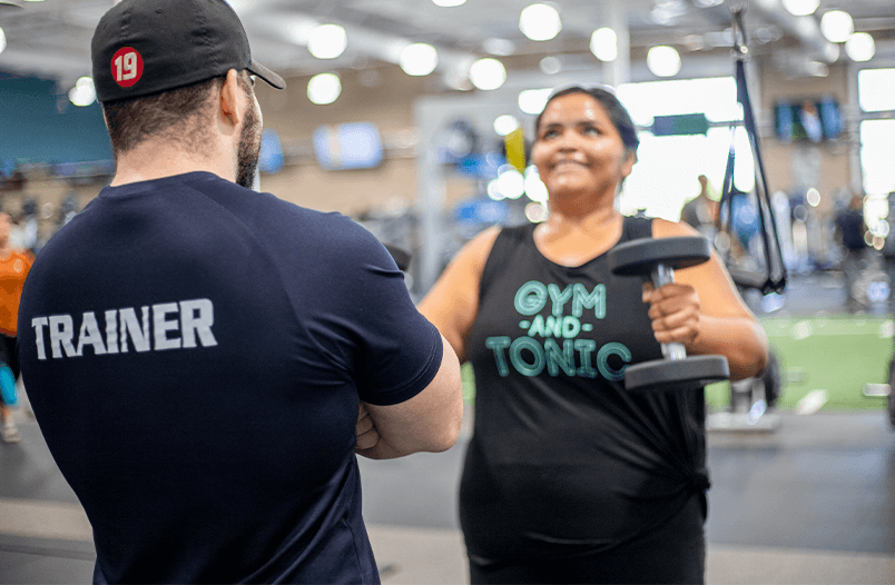 Personal trainer helping a client with dumbbell raises